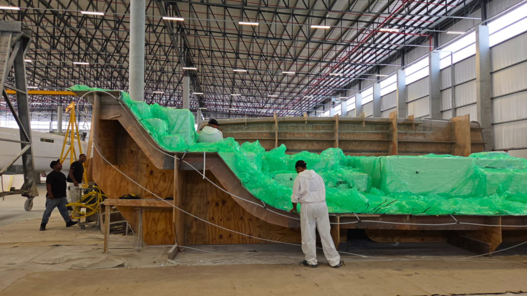 A photograph of the VOYAGE Yachts composites team working with the VOYAGE 510 hull-side infusion